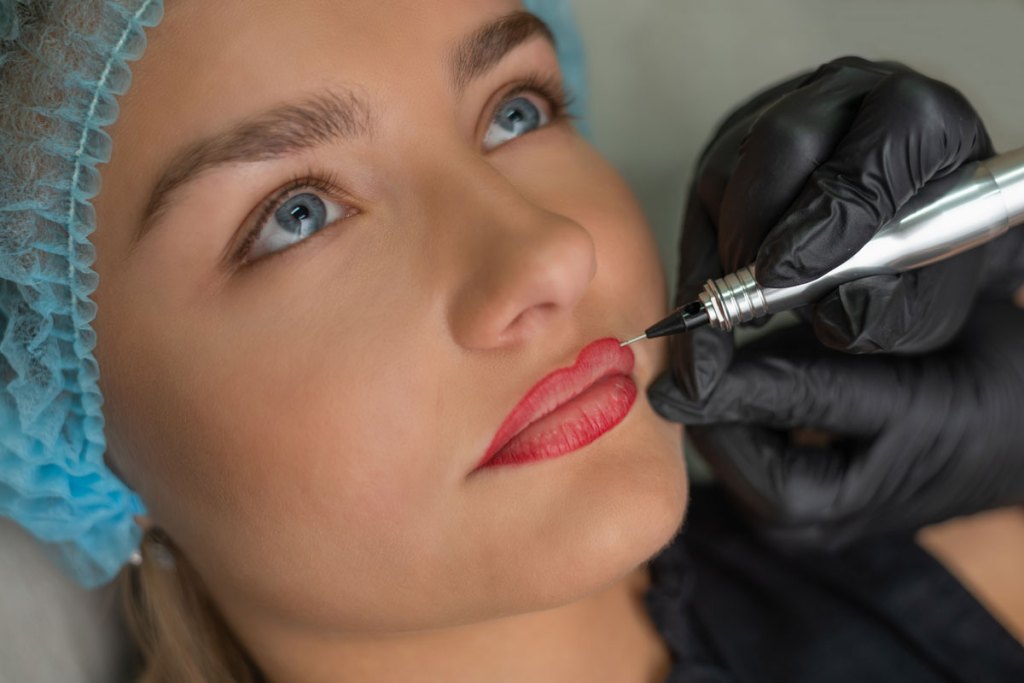 Frau, die sich die Lippen rot tätowieren lässt.