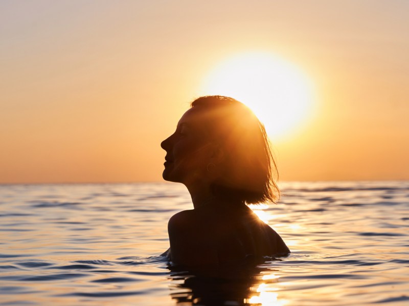 Frau im Meer im Sonnenuntergang