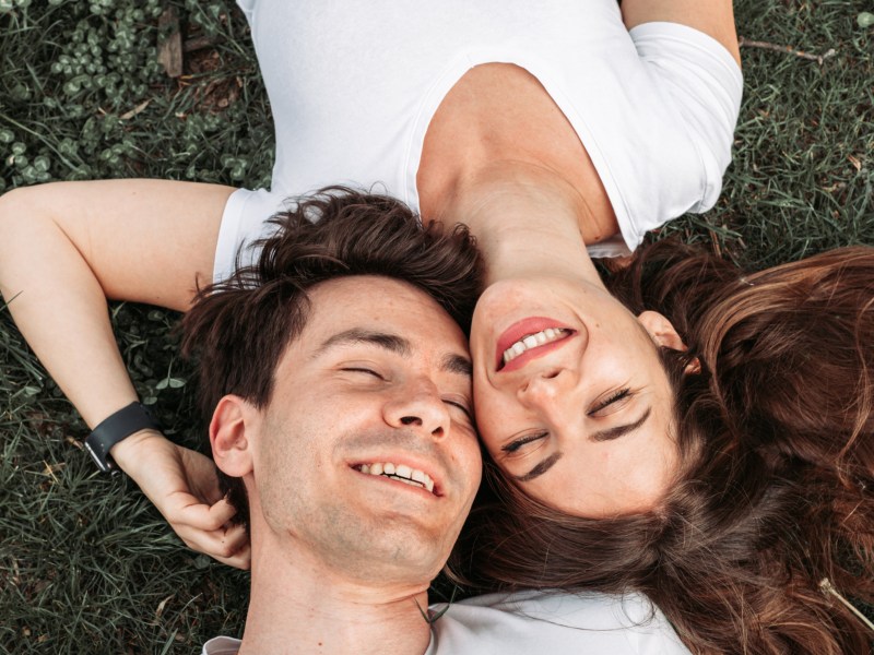 Frau und Mann, die verliebt auf dem Rasen liegen und lachen