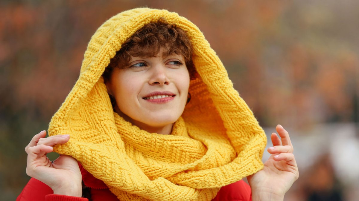 Frau mit warmen Schal beim Herbstspaziergang.