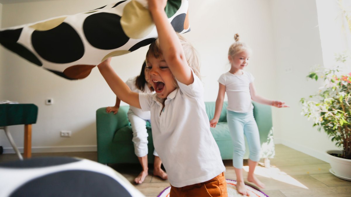 Kinder spielen Wild im Wohnzimmer und werden Kissen.