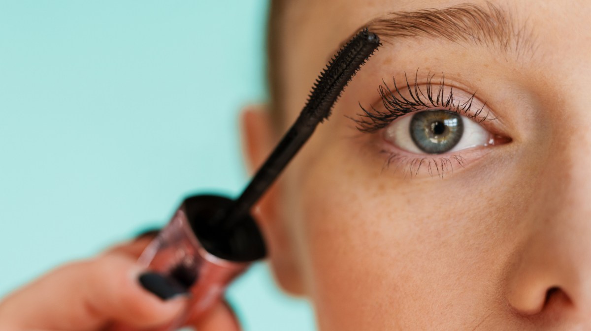 Frau tuscht sich mit Mascara die Wimpern.