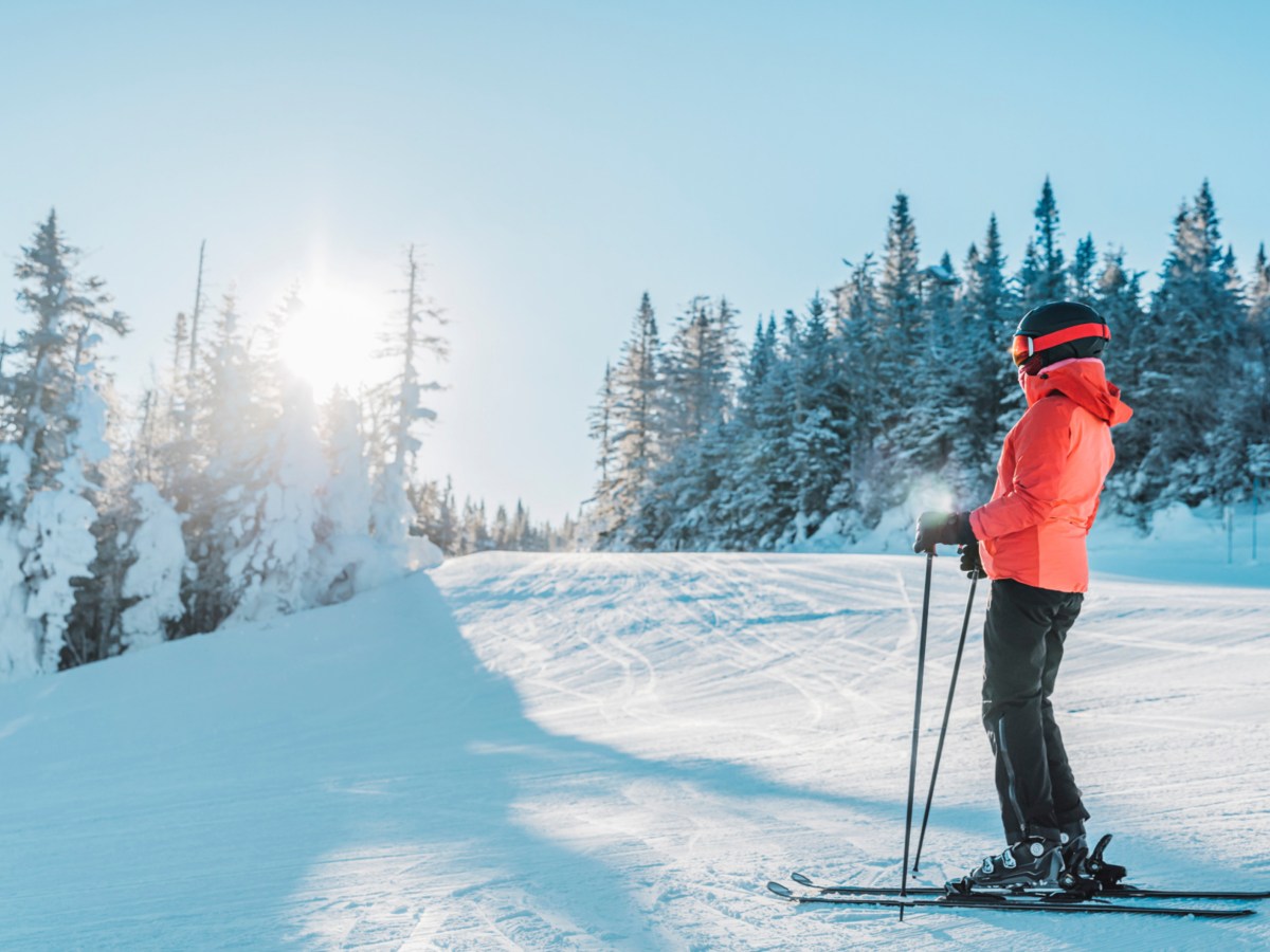 Frau mit Ski-Ausrüstung im Skigebiet bie Sonnenschein