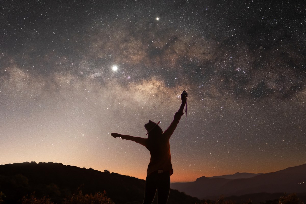 Eine Frau steht unter dem Sternenhimmel.