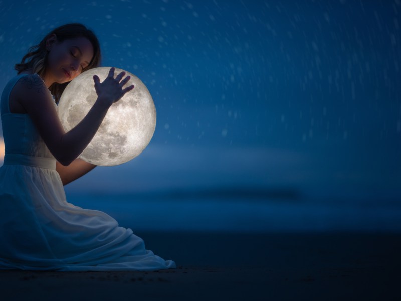 Frau im weißen Kleid umarmt Mond