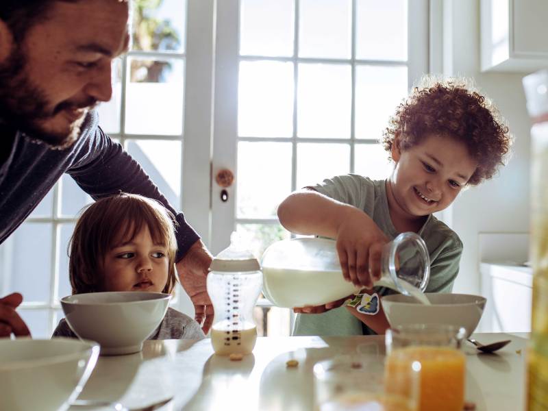 Vater und Kinder bereiten sich ihr Frühstück vor.