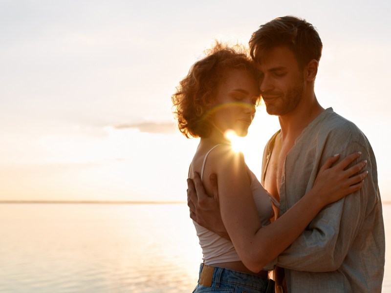 Mann und Frau im Sonnenuntergang, die sich gegenseitig umarmen