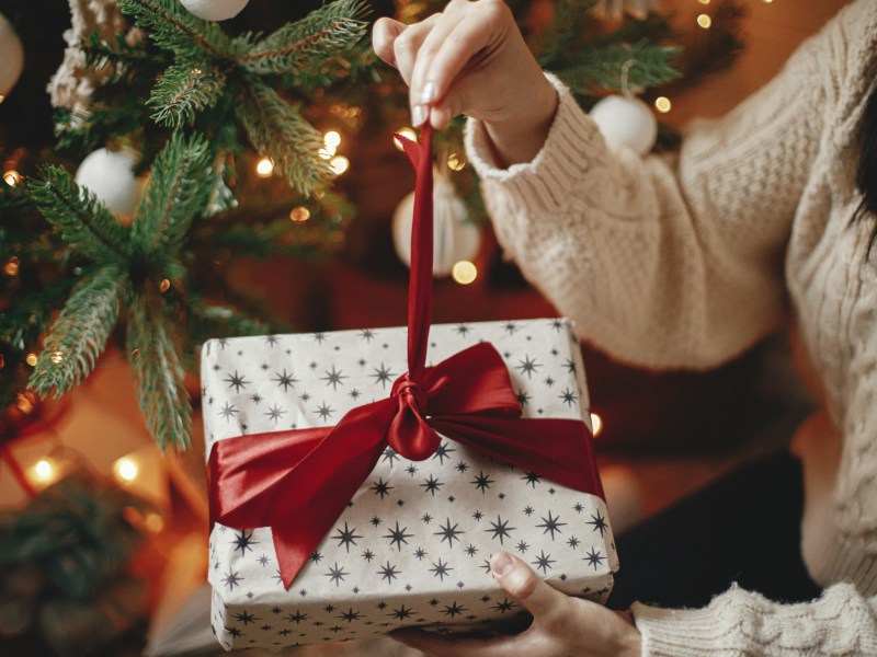 Eine Frau packt ein Weihnachtsgeschenk aus