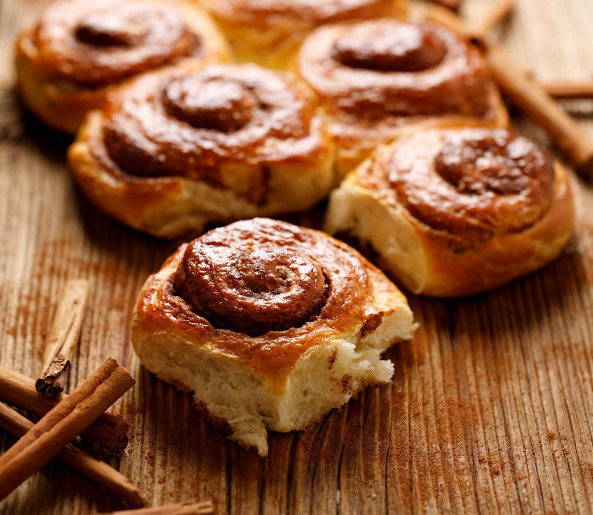 Traditionelle spiralförmige Zimtschnecken auf einem Holztisch, Nahaufnahme