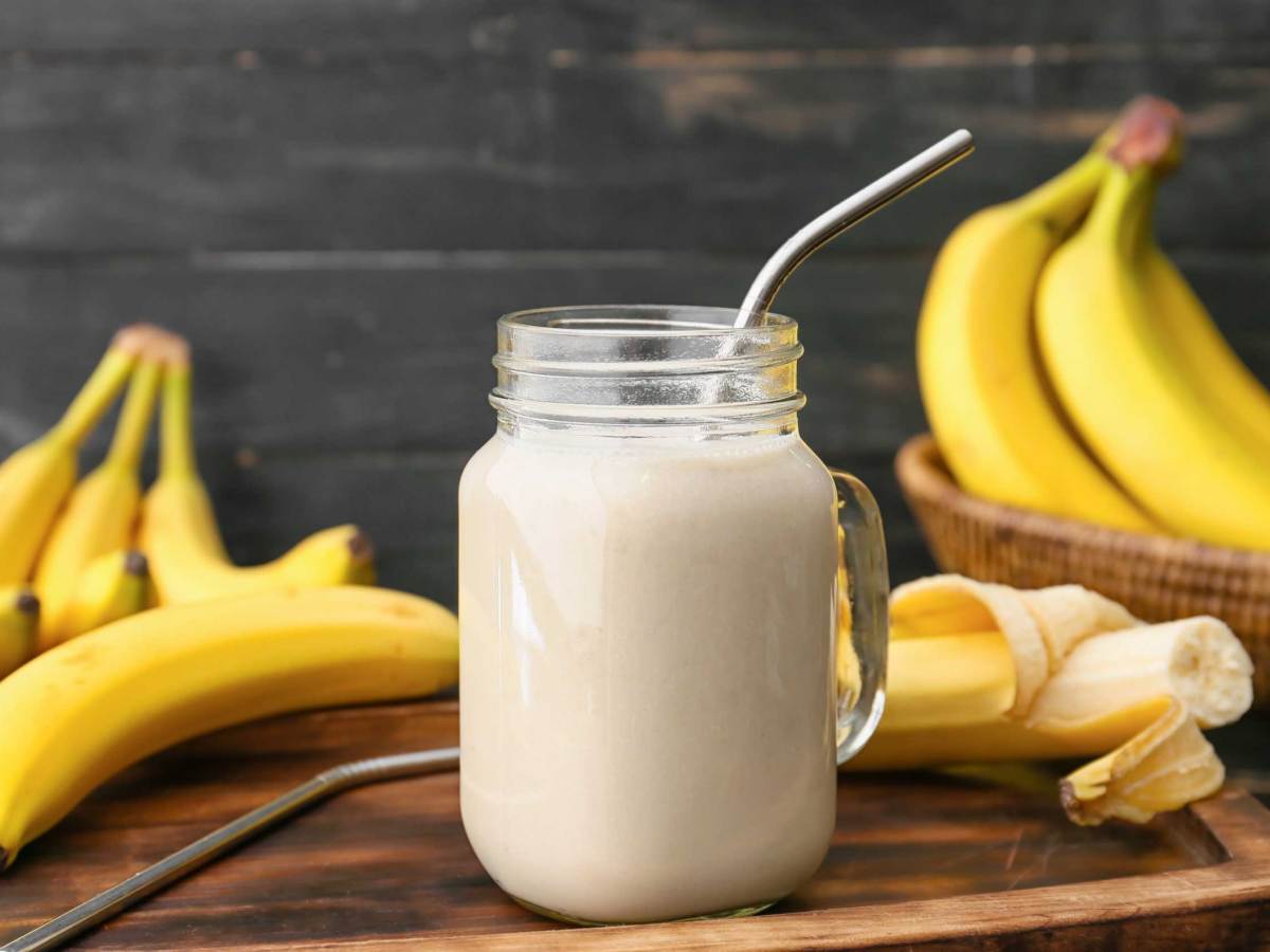 Einweckglas mit leckerem Bananensmoothie auf hölzernem Hintergrund