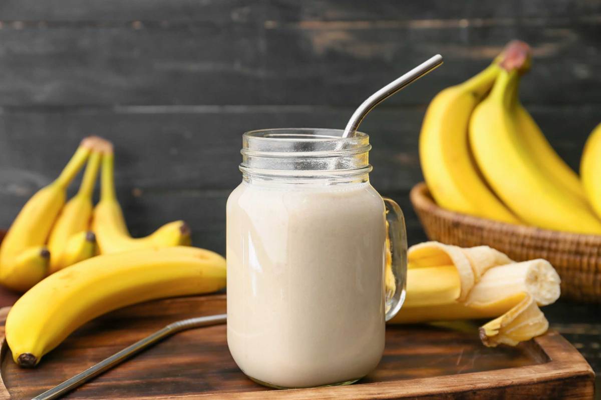 Einweckglas mit leckerem Bananensmoothie auf hölzernem Hintergrund