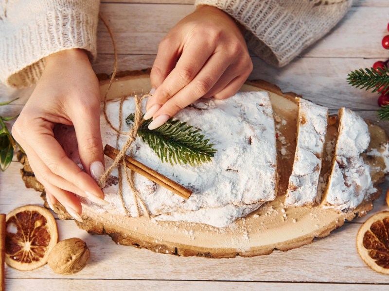 Frau dekoriert Stollen, der auf dem Weihnachtstisch steht