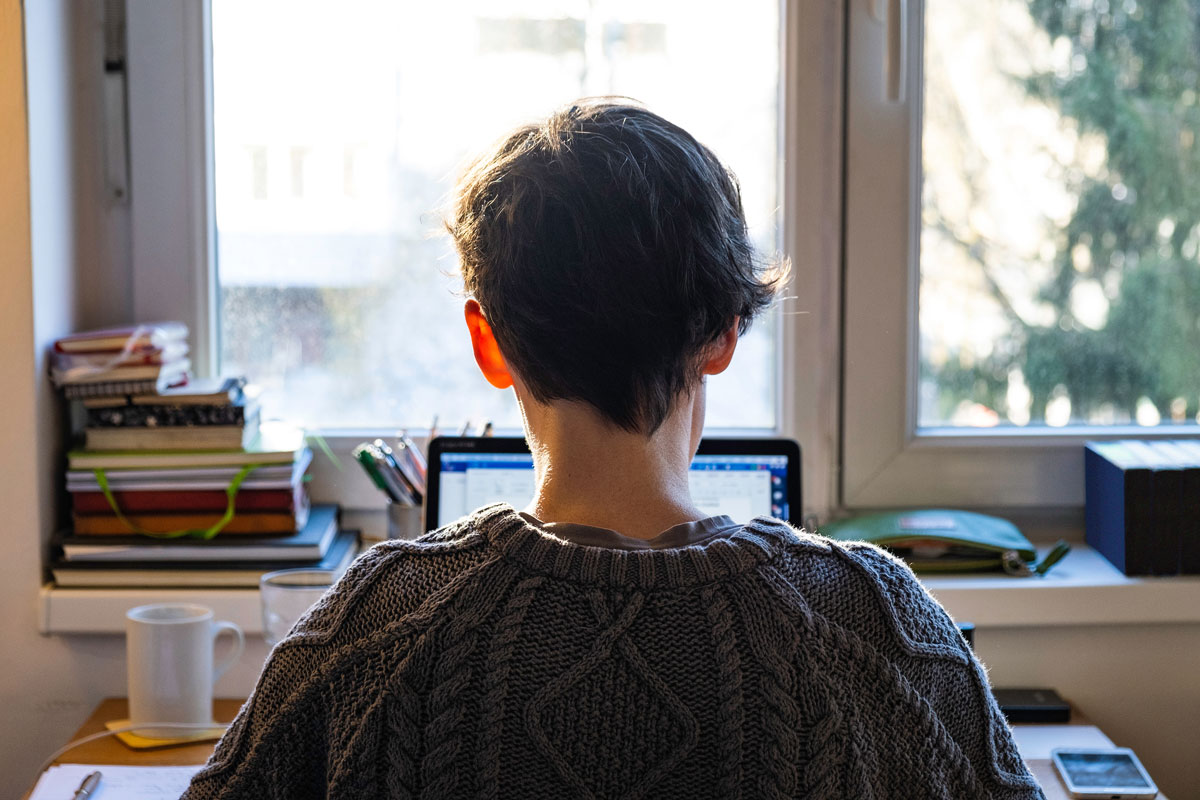 Eine Frau sitzt am Schreibtisch und schaut aus dem Fenster.