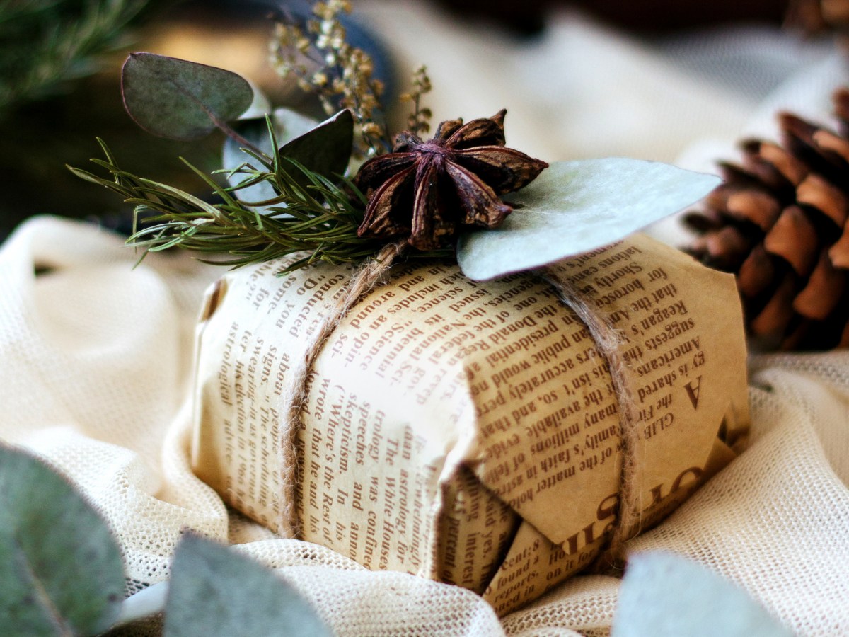 Ein Weihnachtsgeschenk eingepackt in Zeitungspapier und mit Kordel und Naturmaterialien dekoriert.
