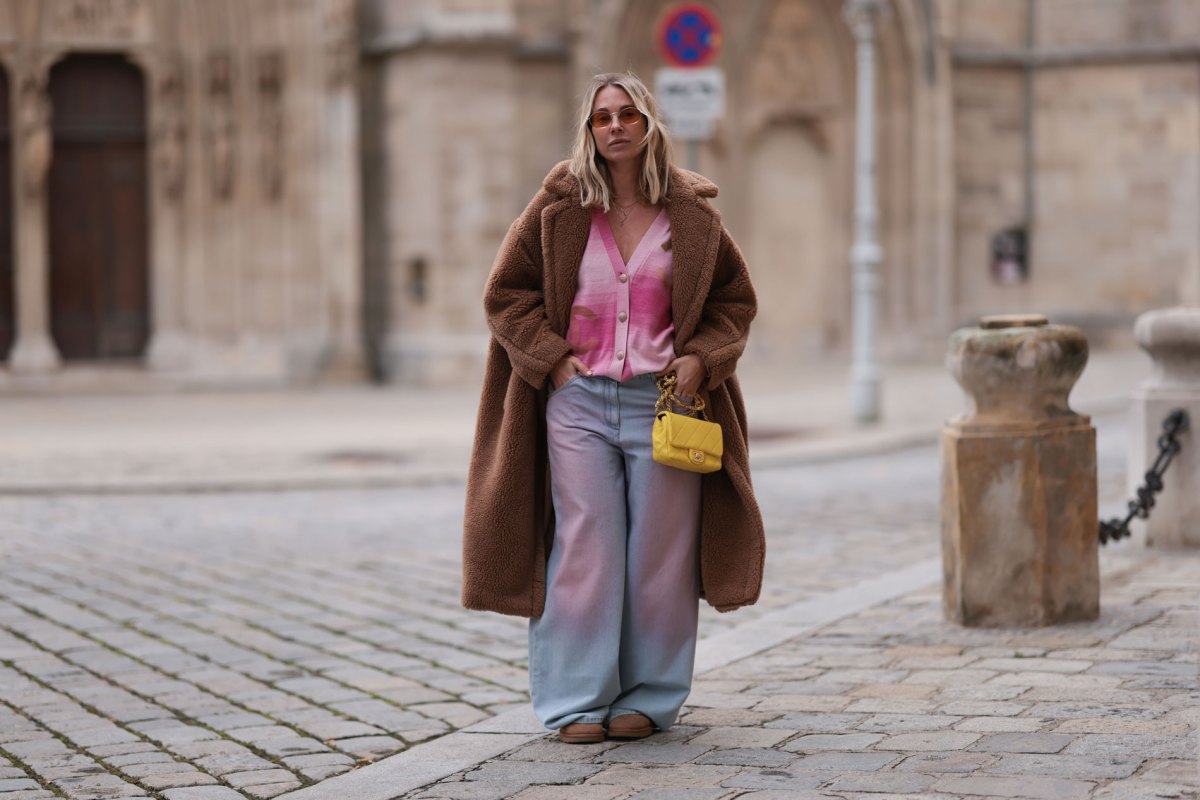 Karin Teigl trägt einen rosa Cardigan und einen braunen Teddymantel zur weiten Jeans.