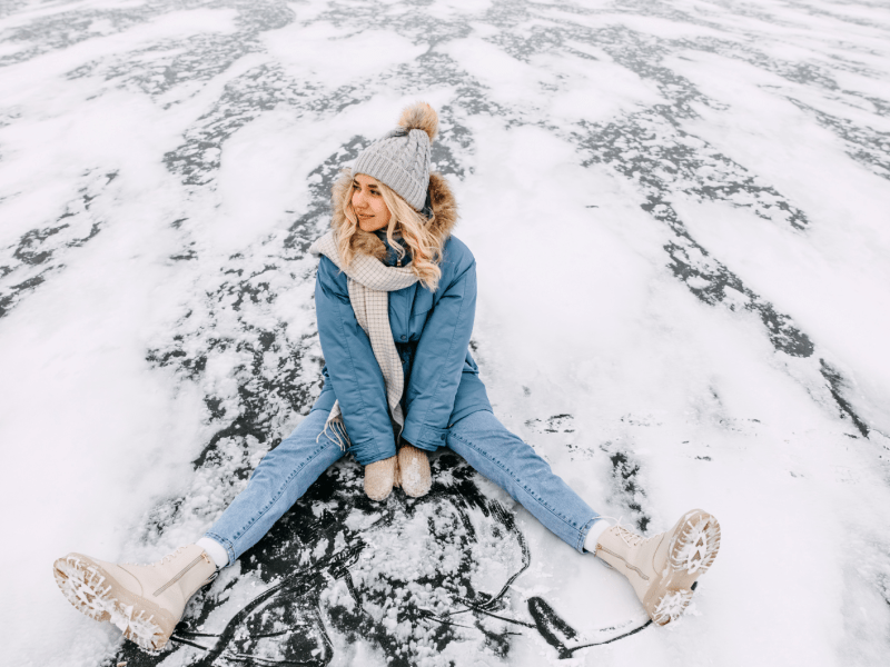 Frau im Schnee auf einer Eisplatte die lächelt und zur Seite schaut