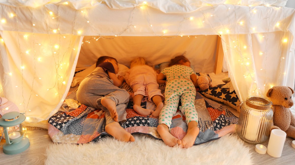 Drei Kinder unterschiedlichen Alters schlafen in einer Höhle im Zimmer.