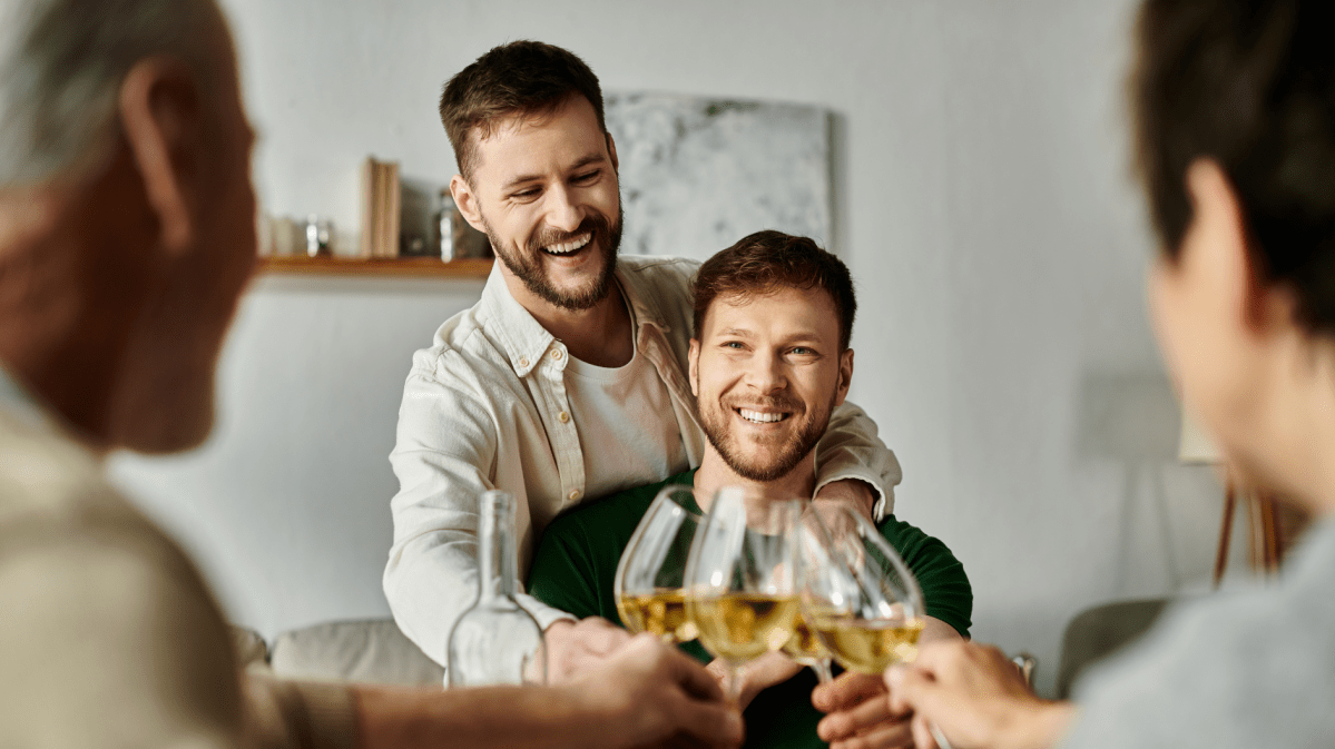 Zwei Männer, die mit einem Weinglas mit zwei anderen Menschen anstoßen.