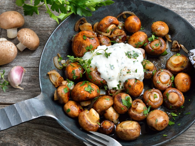 Champignons mit Knobisosse in einer Pfanne.