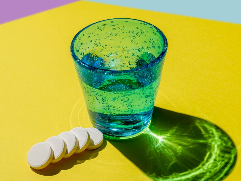 Grünes Glas mit Brausetabletten um Kater vorbeugen zu können
