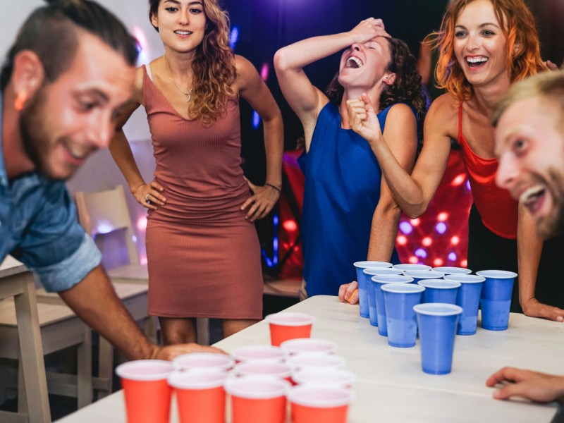 Gruppe von jungen Leuten spielen Beer Pong auf Party.