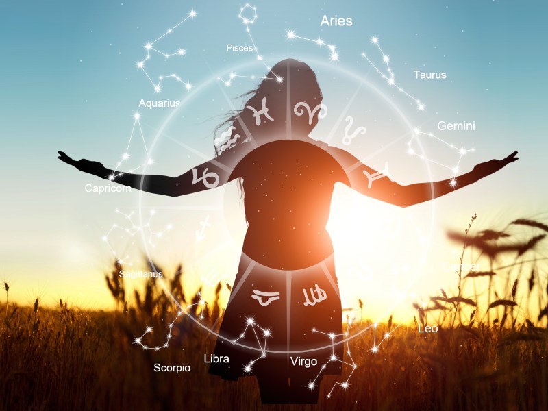 Frau im Weizenfeld bei Sonnenuntergang und Sternzeichen-Symbole