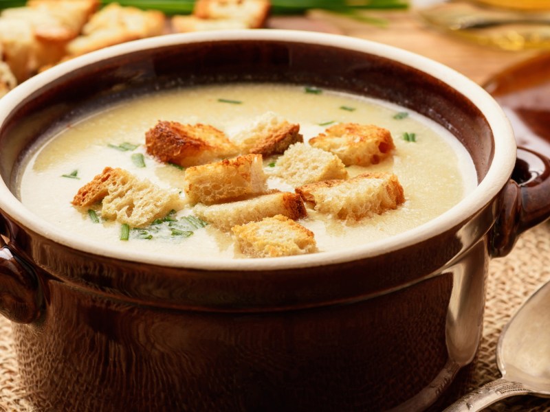 Käse-Suppe mit Croûtons in einem braunen Suppentopf.