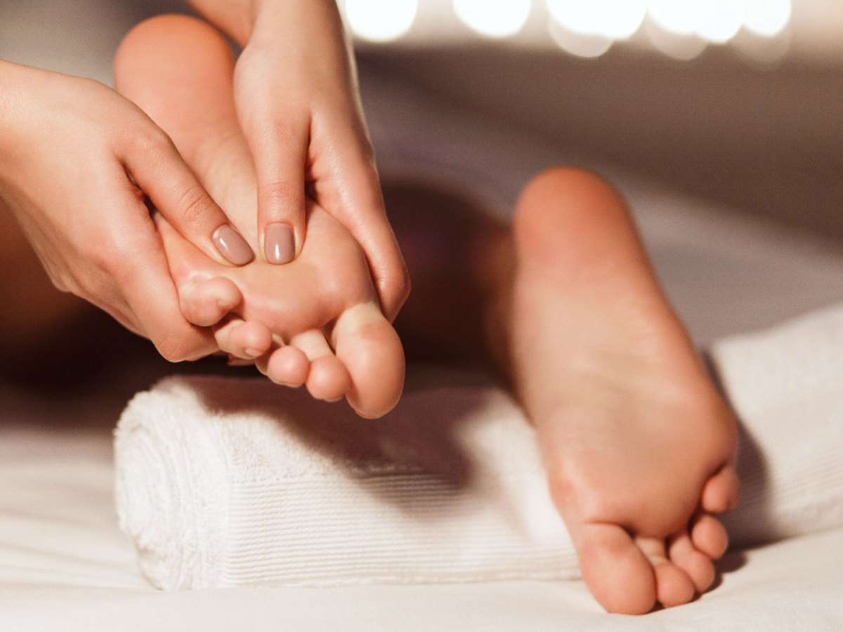 Fußmassage: Manikürte Finger massieren Füße