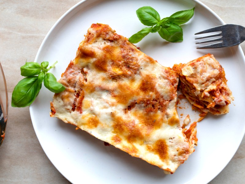 Vegetarische Gemüselasagne, ein Stück auf weißem Teller.