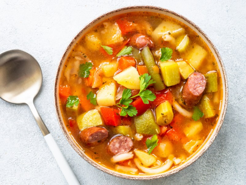 Suppe mit Mettwürstchen, Kartoffeln und Tomaten.