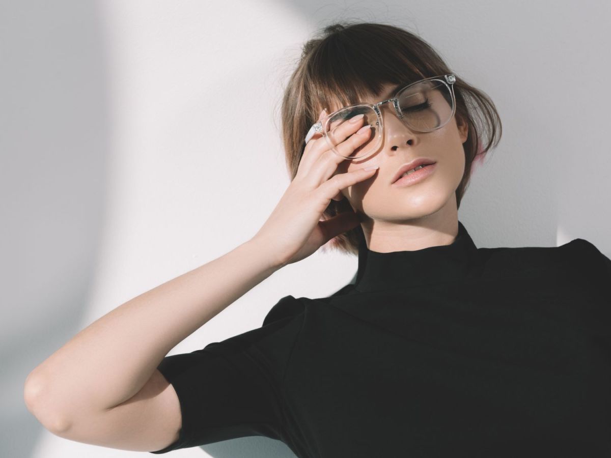 Frau mit Brille hält sich ein Auge zu, Symbolbild für introvertiert sein