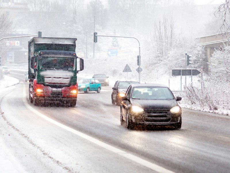 Verschneite Straße darauf Autos und LKW