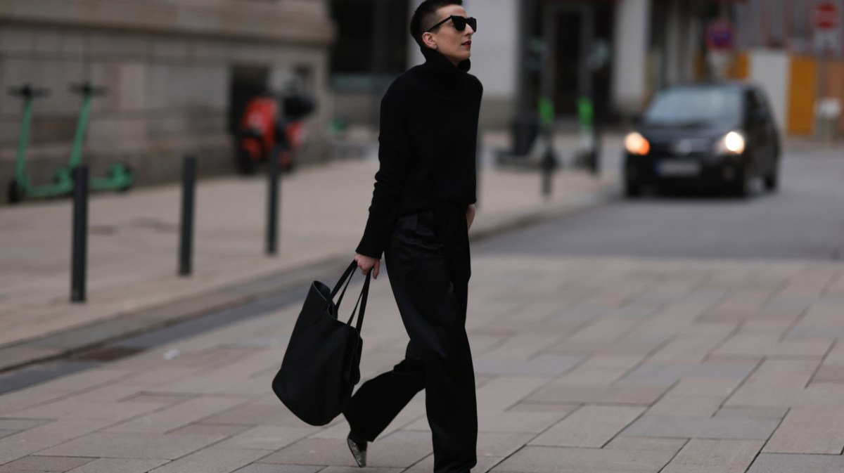 Frau ganz in schwarz gekleidet, street style, hält schwarzen Shopper in Hand.