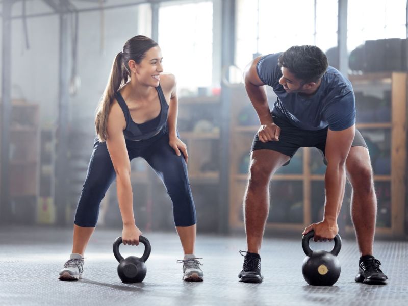 Mann und Frau heben Hanteln beim Sport.