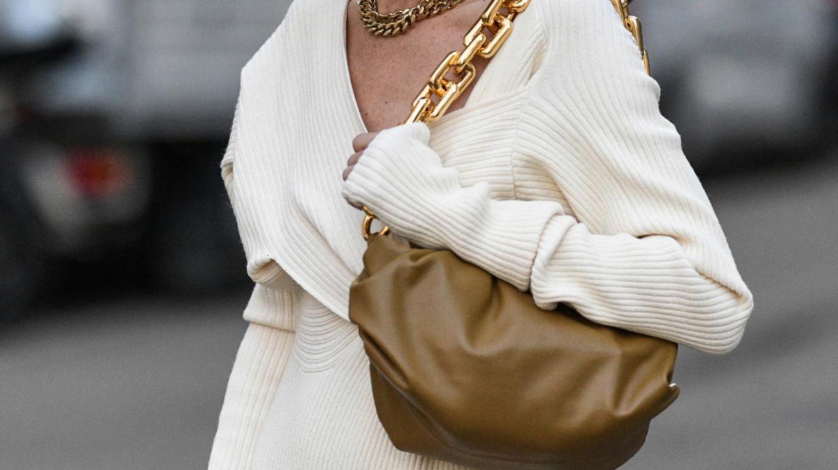 Frau mit weißem Pullover und beiger Lederhandtasche.