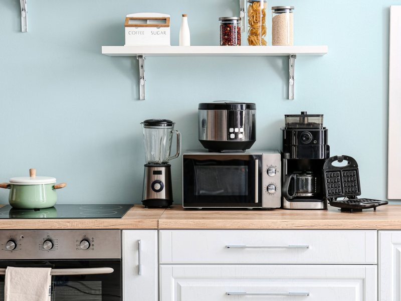 Küchenzeile auf der verschiedene Geräte stehen, wie Mikrowelle und Mixer.