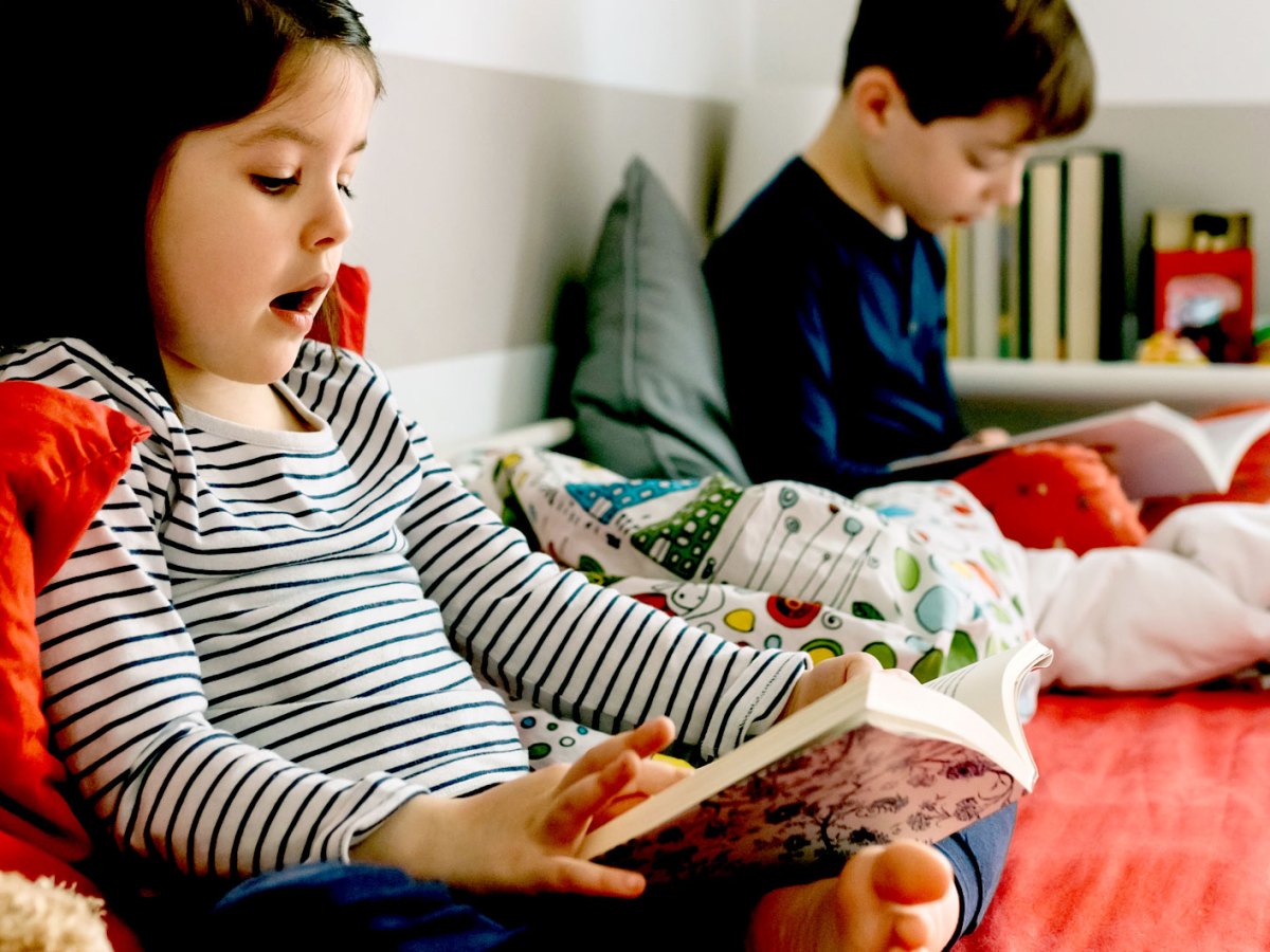 Zwei Kinder auf einem Hochbett lesen in Büchern.