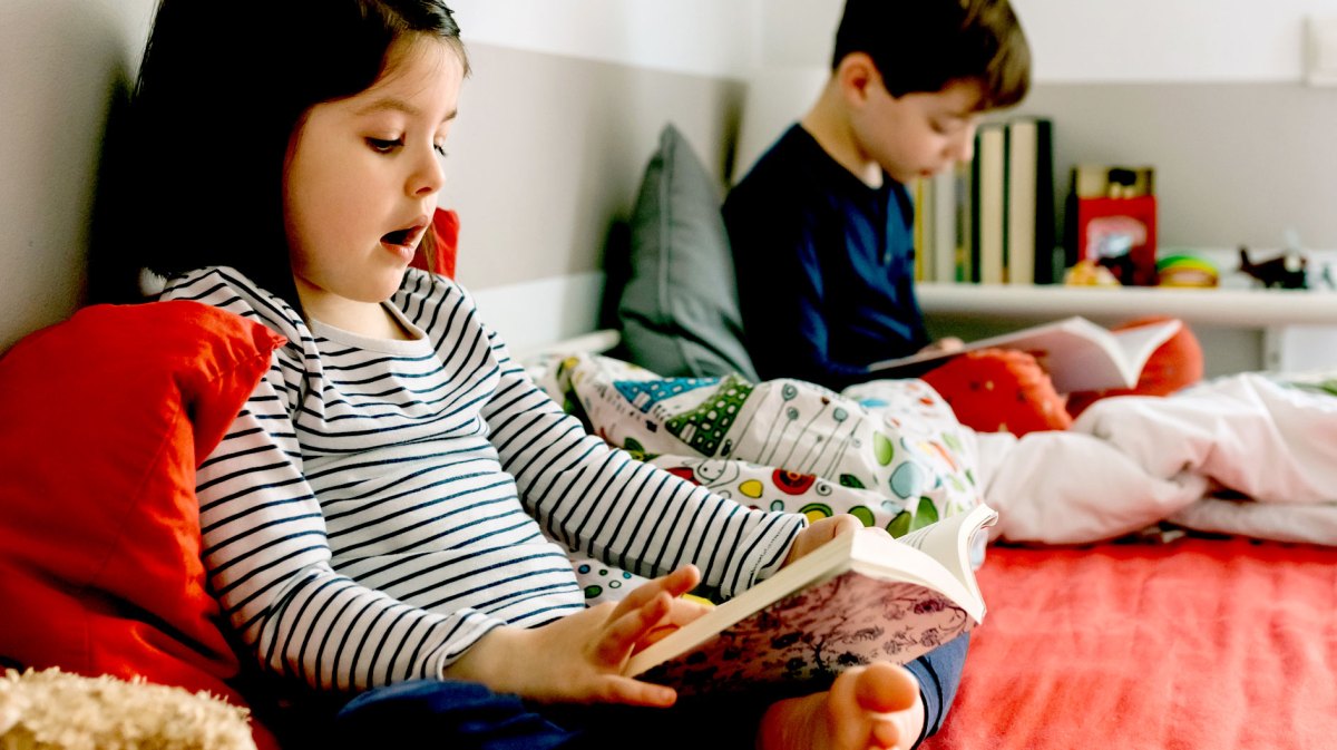 Zwei Kinder auf einem Hochbett lesen in Büchern.