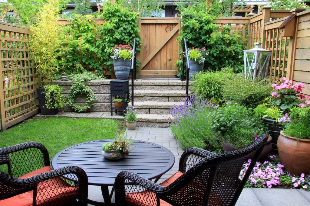 Treppe im Garten mit Rasen, Beeten und einer Sitzecke im Vordergrund