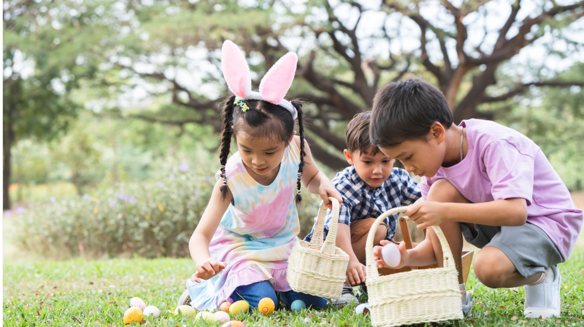 Kinder suchen im Garten mit Osterkörben nach Ostereiern