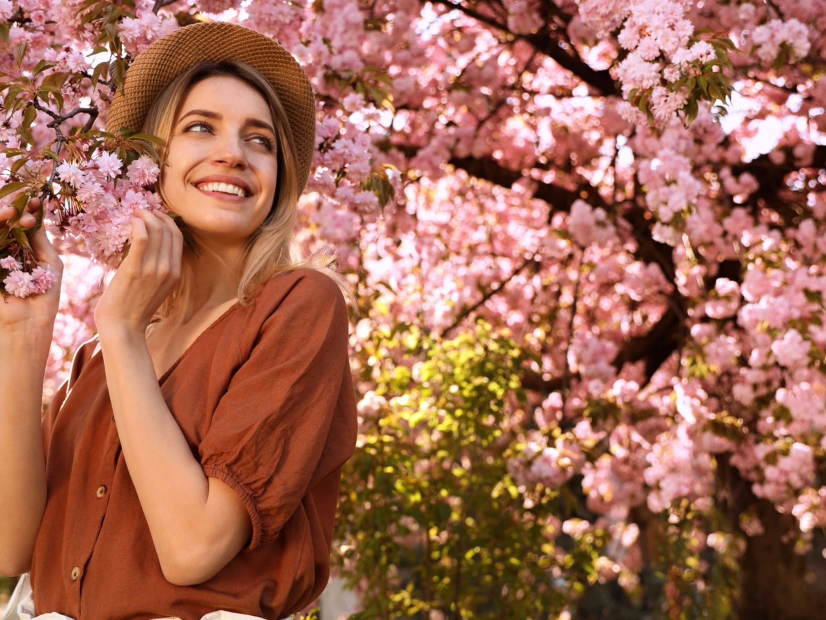 Frau mit Hut unter Kirschblütenbaum
