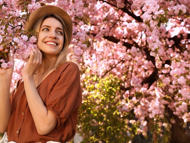 Frau mit Hut unter Kirschblütenbaum