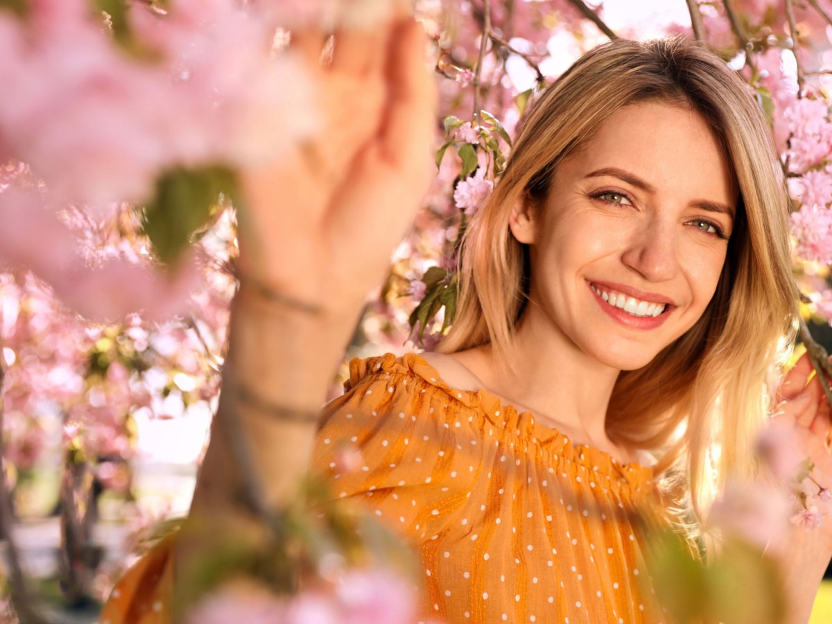 Frau in gelber Bluse zwischen Kirschblüten