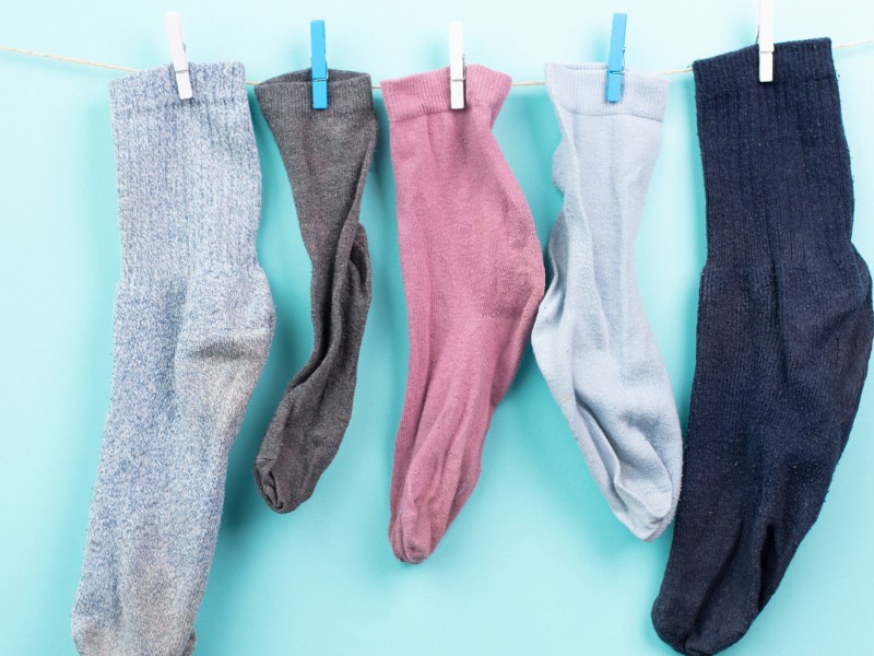 Einzelne alte Socken hängen an einer Wäscheleine.