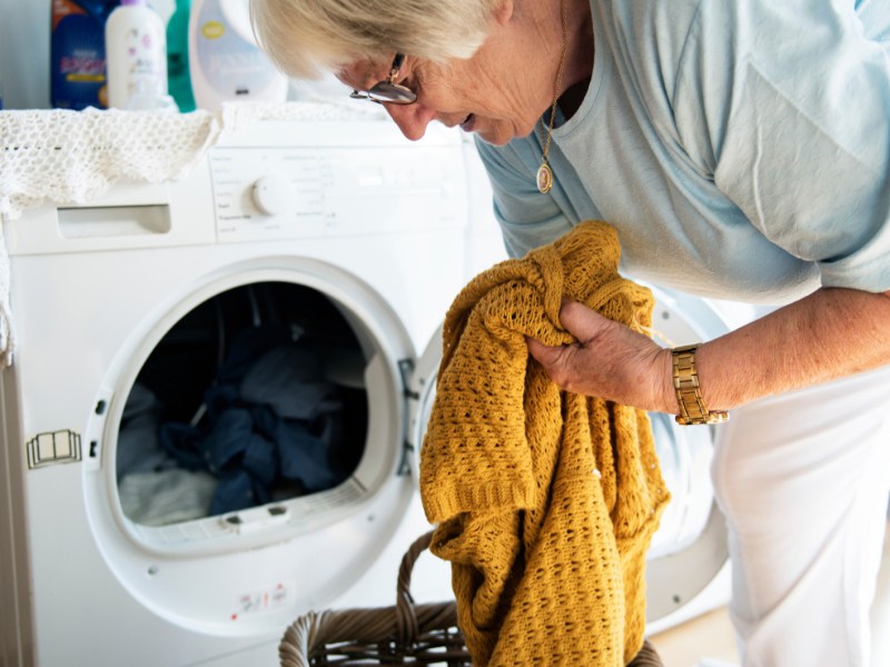 Waschmaschine stinkt: Ältere Frau räumt Waschmaschine aus.