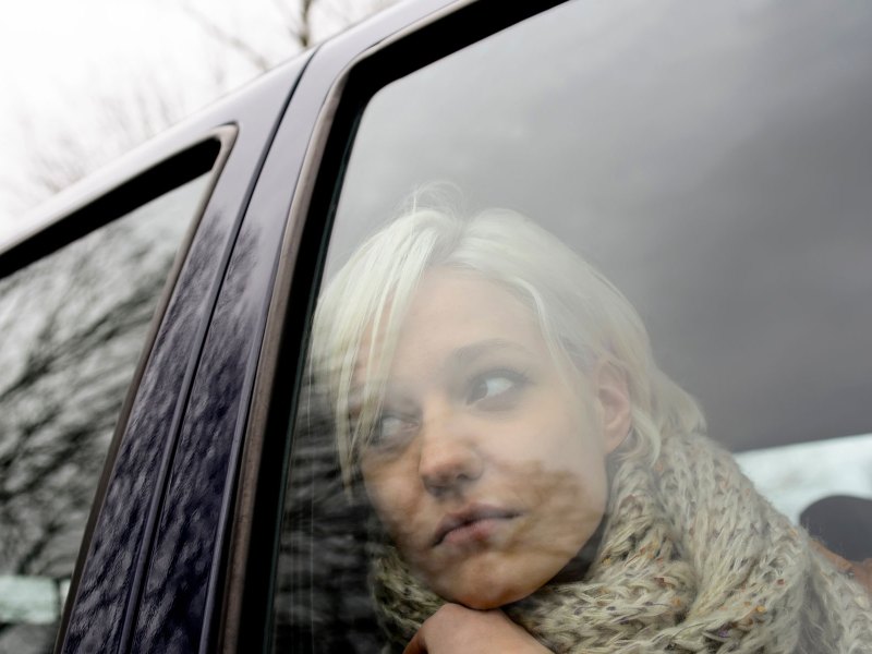 Frau schaut traurig aus einem Autofenster