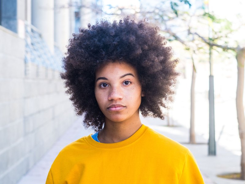 Frau mit Afro mit gelbem Pullover