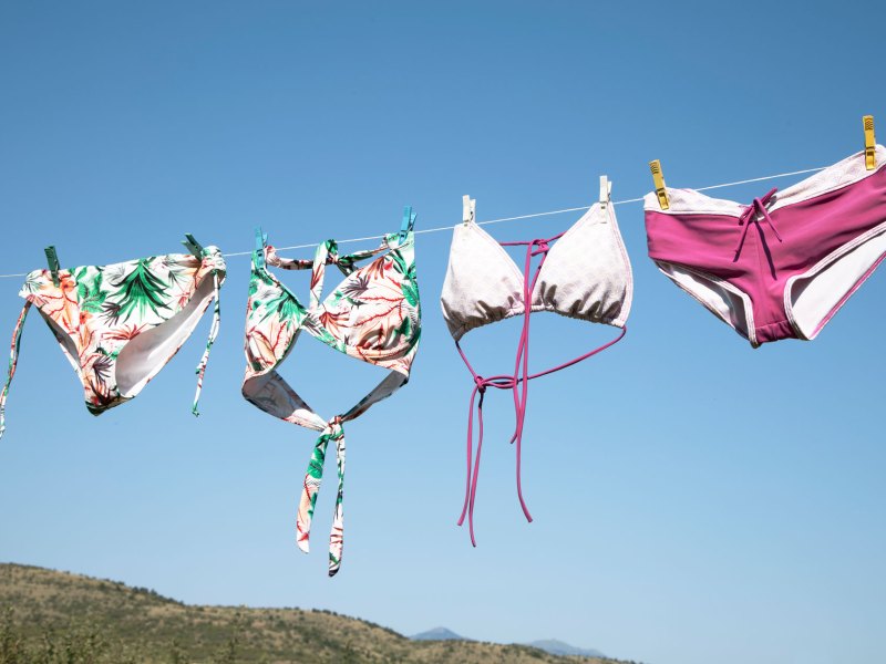 Bikinis, die in der Sonne auf einer Wäscheleine trocknen und deren Farben sehr verblasst sind.
