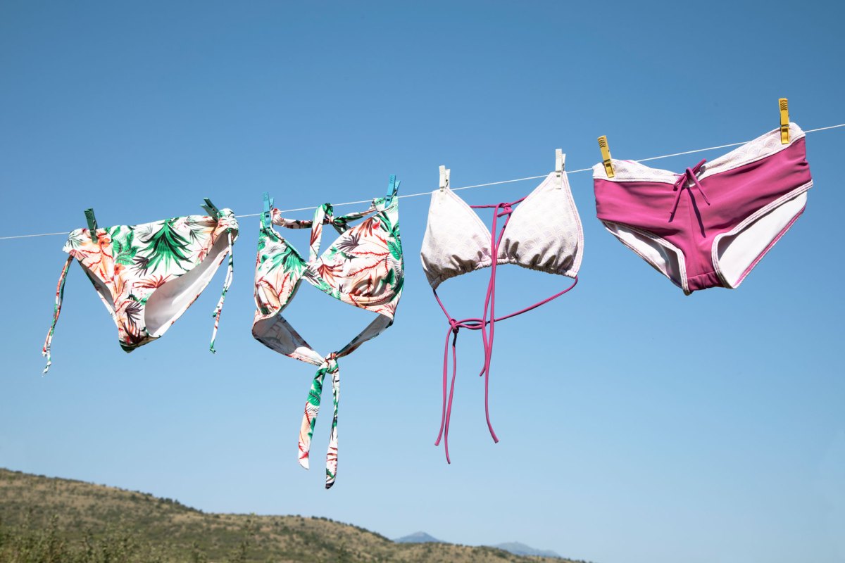 Bikinis, die in der Sonne auf einer Wäscheleine trocknen und deren Farben sehr verblasst sind.