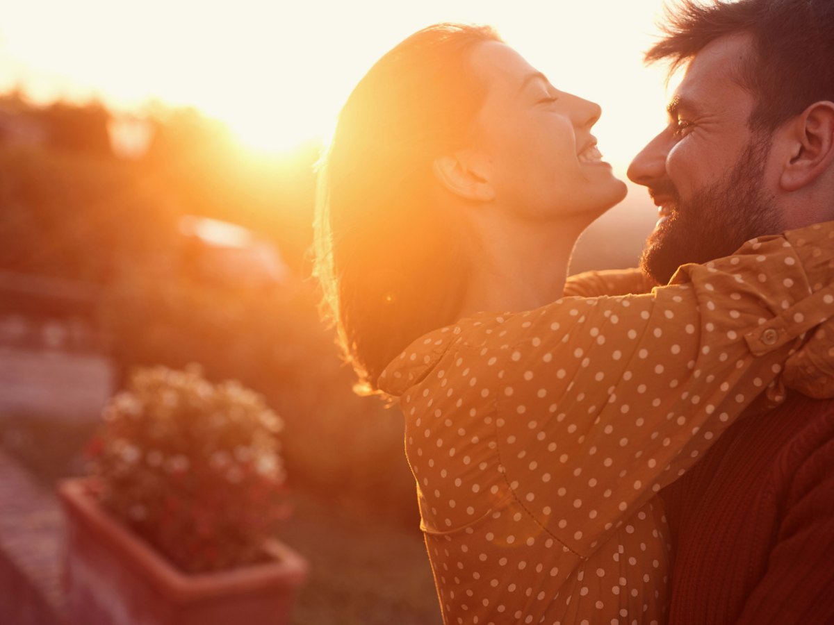 Frau und Mann schauen sich verliebt an bei Sonnenuntergang